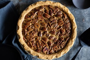 Overhead shot of a whole pecan pie on a dark grey surface.