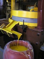 Photo of Raye's mustard mill with yellow mustard paste dripping into a container..