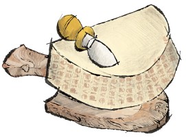 Wedge of Piave cheese on a wooden cheese board with a cheese knife